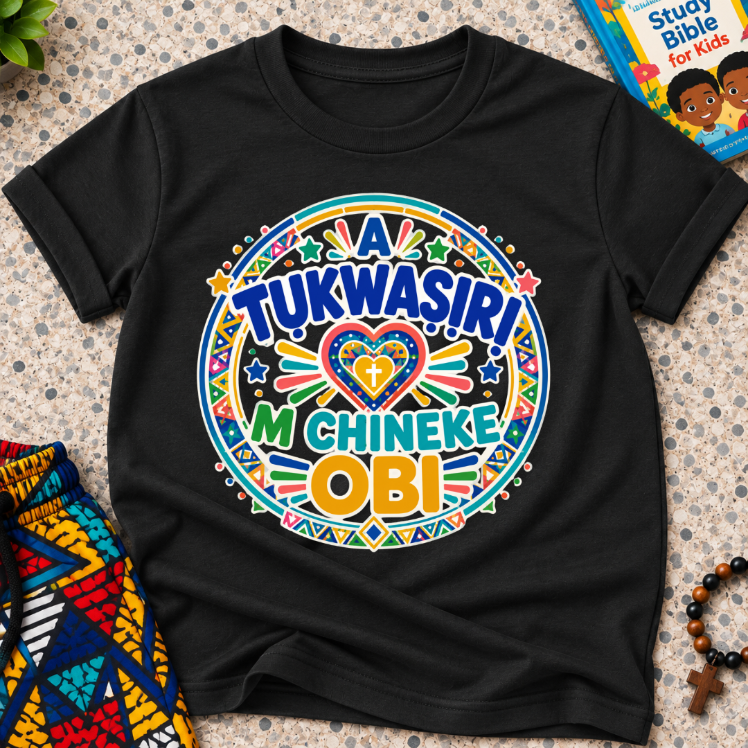 A Tukwasiri M Chineke Obi Igbo-language kids shirt in black featuring colourful lettering, a heart motif, and circular decorative patterns

