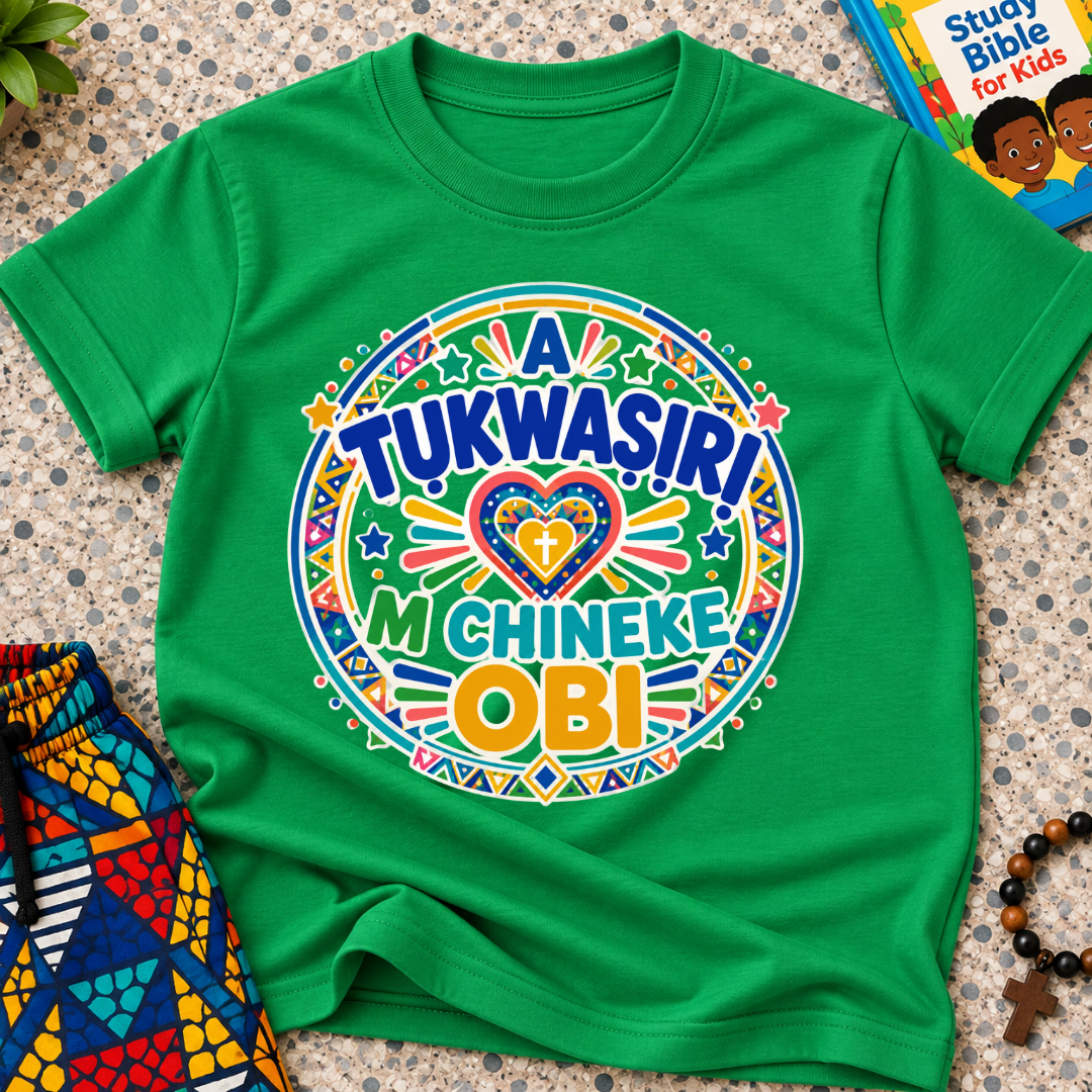 A Tukwasiri M Chineke Obi Igbo-language kids shirt in green featuring colourful lettering, a heart motif, and circular decorative patterns
