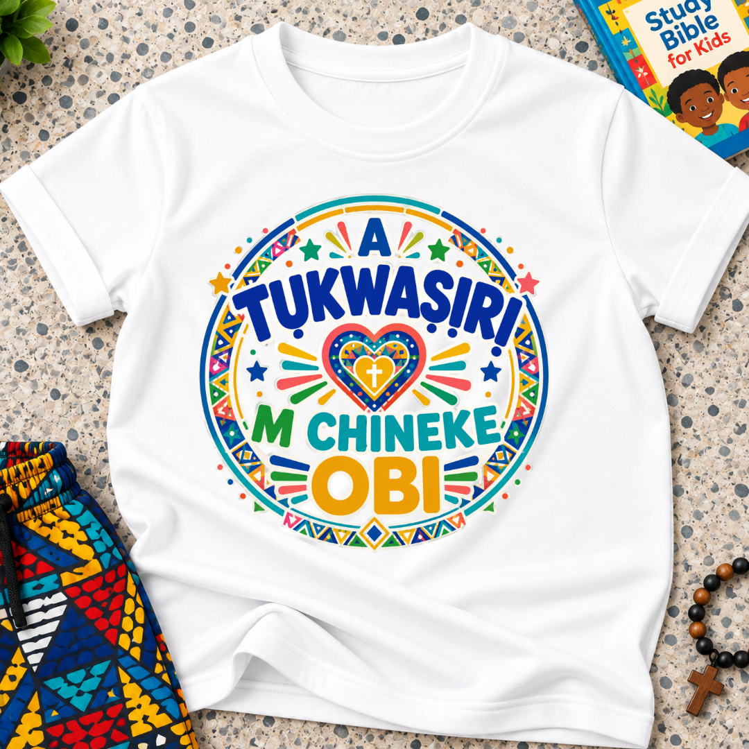 A Tukwasiri M Chineke Obi Igbo-language kids shirt in white featuring colourful lettering, a heart motif, and circular decorative patterns
