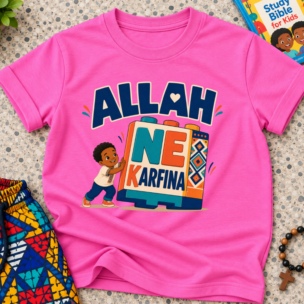 Allah Ne Ƙarfina Hausa-language kids shirt in pink featuring bold lettering and a child beside colourful blocks
