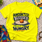 Anointed Blessed Still Hungry Christian kids shirt in yellow featuring bold lettering and food-inspired artwork
