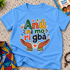 Anụ Ni mo ri Gba kids shirt in light blue featuring colourful lettering, raised hands, and decorative artwork
