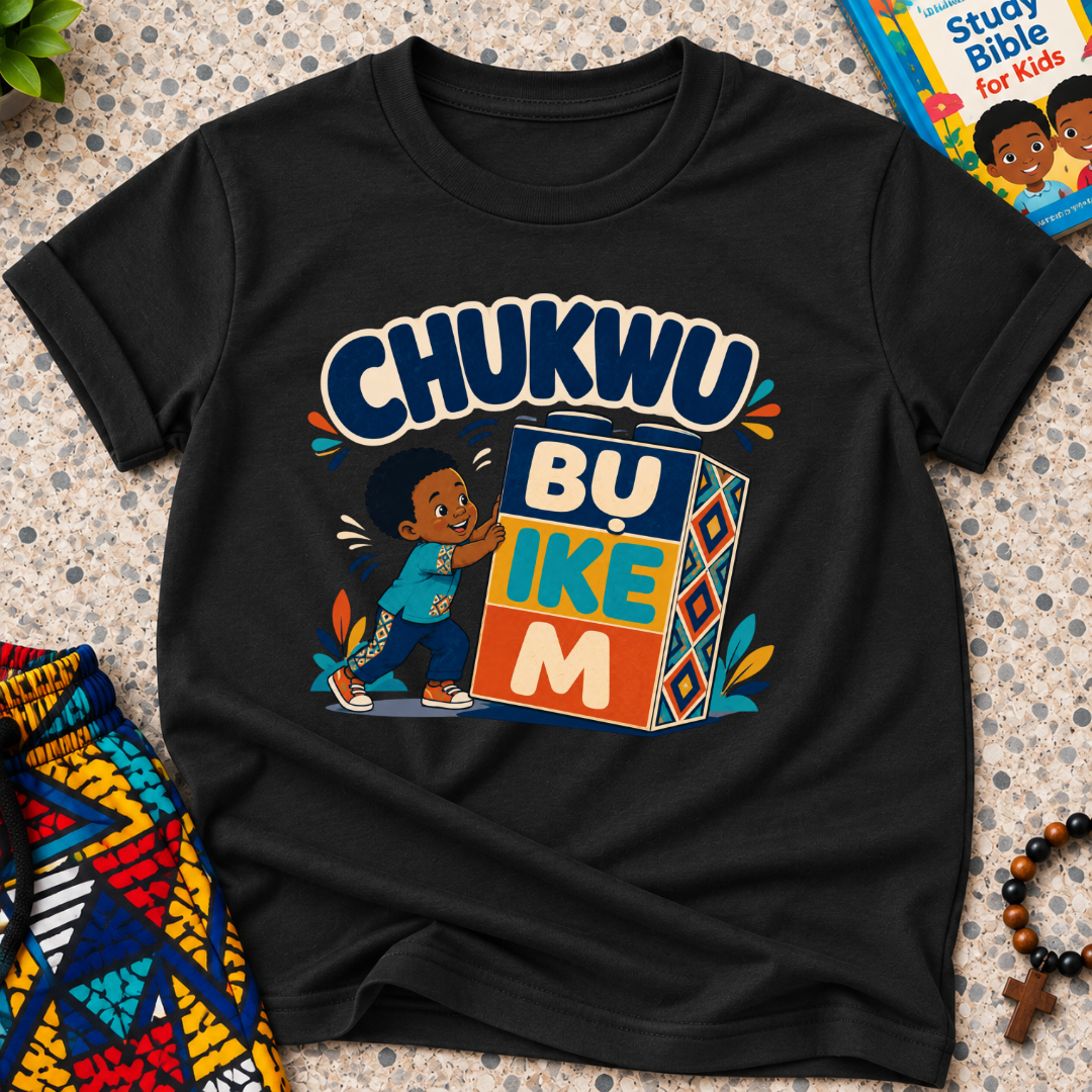 Chukwu Bụ Ike M Igbo Christian kids shirt in black featuring bold lettering and a child beside colourful blocks
