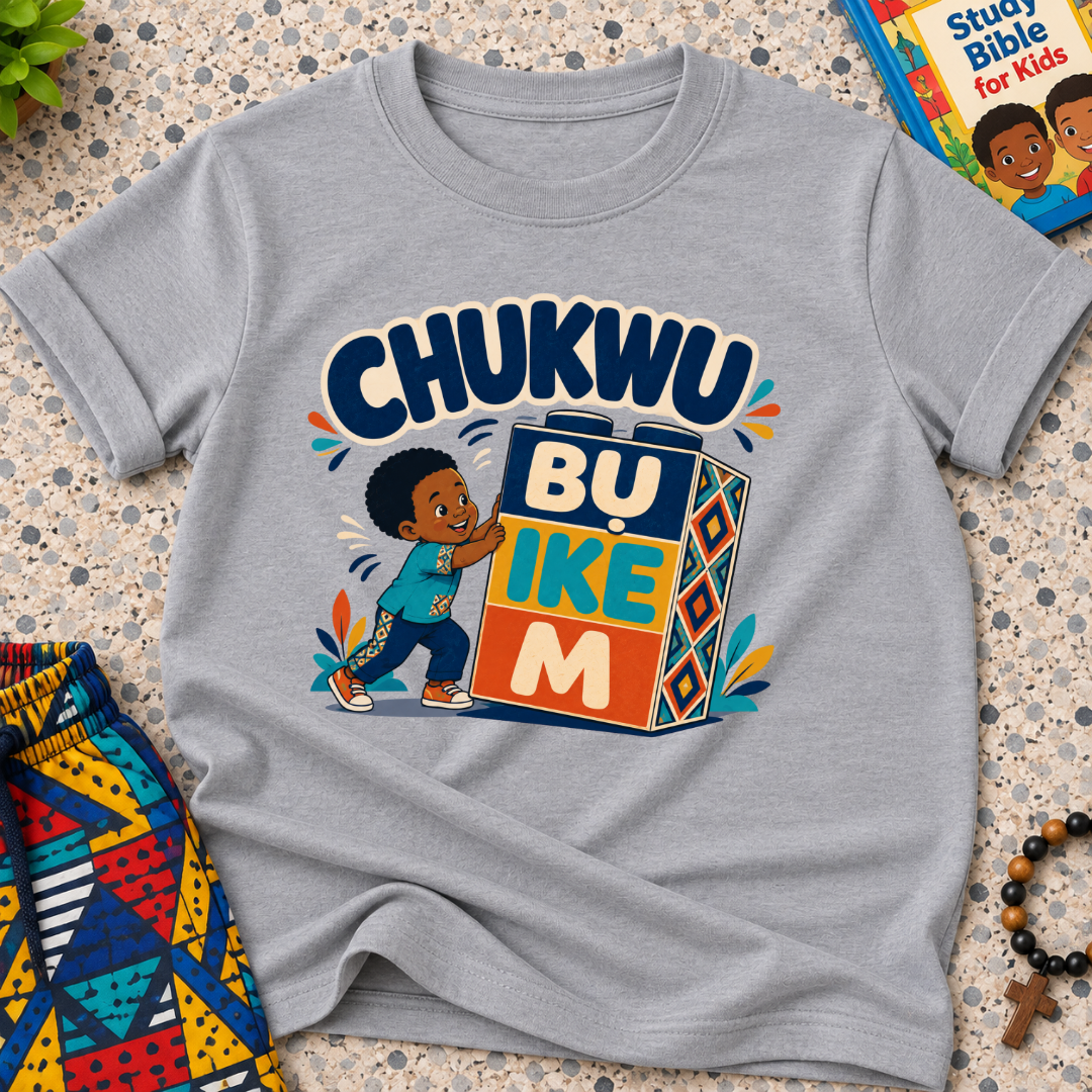 Chukwu Bụ Ike M Igbo Christian kids shirt in grey featuring bold lettering and a child beside colourful blocks
