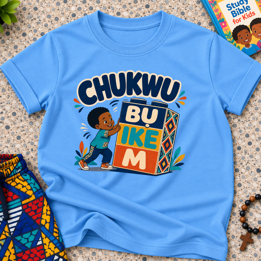Chukwu Bụ Ike M Igbo Christian kids shirt in light blue featuring bold lettering and a child beside colourful blocks
