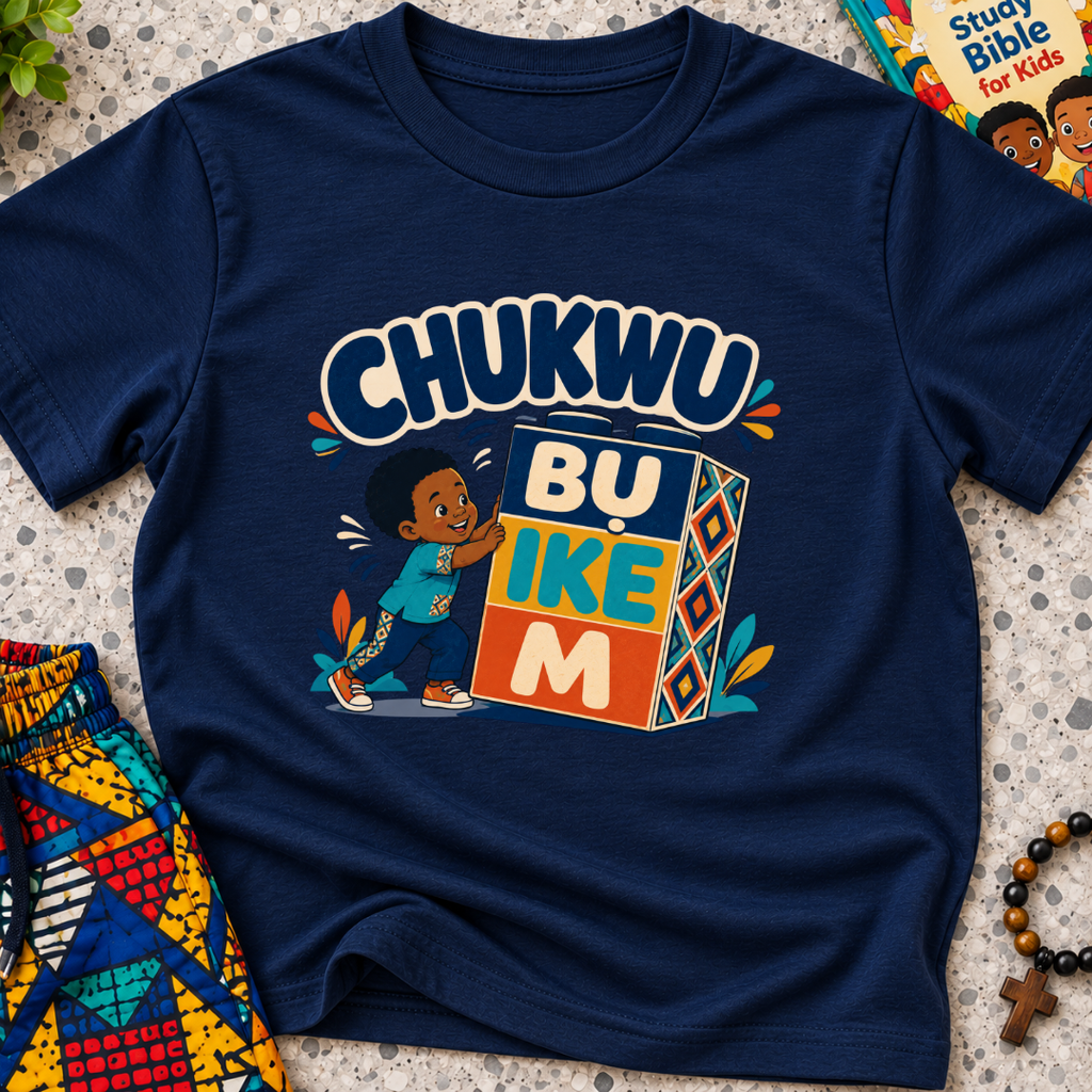 Chukwu Bụ Ike M Igbo Christian kids shirt in navy blue featuring bold lettering and a child beside colourful blocks
