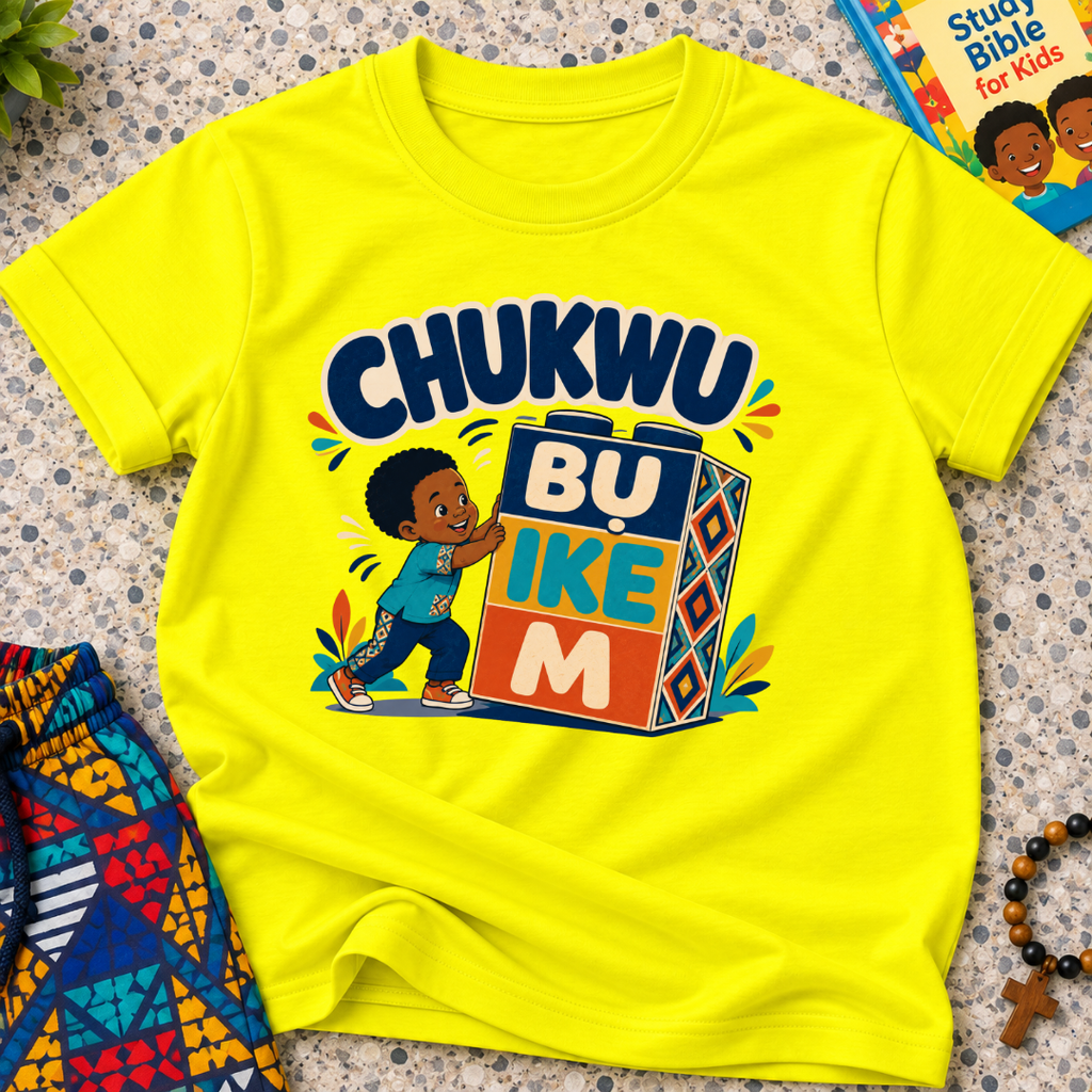 Chukwu Bụ Ike M Igbo Christian kids shirt in yellow featuring bold lettering and a child beside colourful blocks
