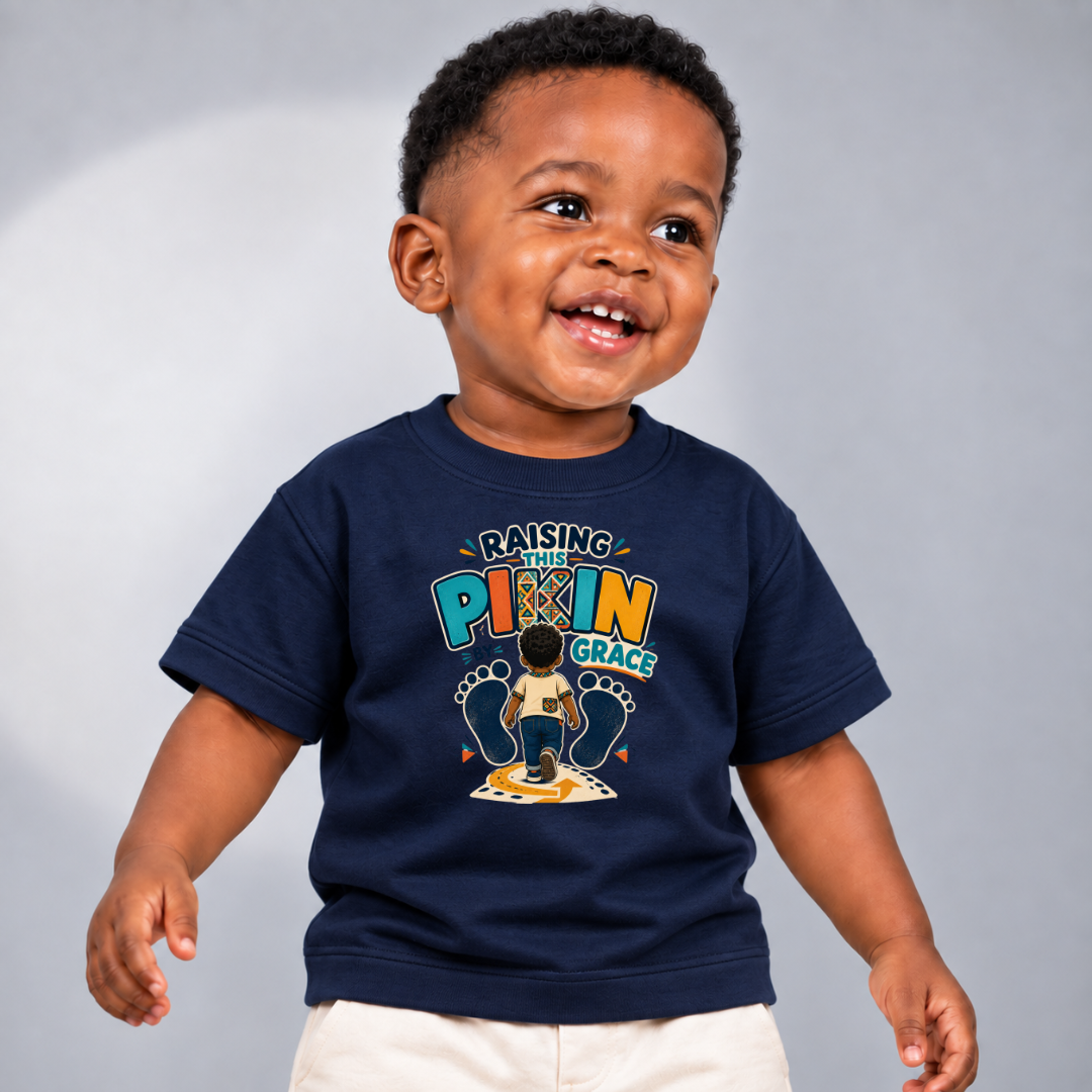 Raising This Pikin by Grace Christian kids shirt in navy blue featuring a child illustration and playful Nigerian parenting message
