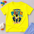 Raising This Pikin by Grace Christian kids shirt in yellow featuring a child illustration and playful Nigerian parenting message
